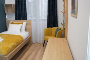 1 dormitorio con 1 cama y 1 silla amarilla en DS36 Budapest-Belvárosi lakás, en Budapest