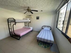 two bunk beds in a room with a ceiling at Depa Roca Sola Acapulco Costera in Acapulco