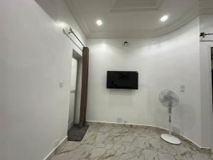 Cette chambre blanche dispose d'un ventilateur et d'une télévision murale. dans l'établissement Kyra’s place, à Rufisque