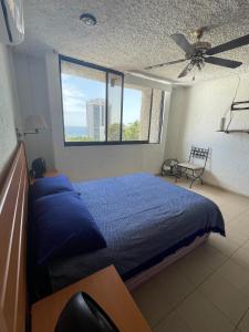 a bedroom with a blue bed and a window at Depa Roca Sola Acapulco Costera in Acapulco