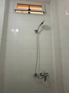 y baño de azulejos blancos con ducha y cabezal de ducha. en Kyra’s place, en Rufisque