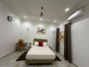 een slaapkamer met een bed en een tafel en een klok bij Kyra’s place in Rufisque +15 foto's