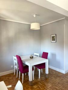 a dining room with a white table and purple chairs at Apartamento en Getxo. Cercano al puerto viejo in Getxo