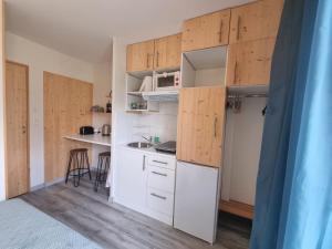 a small kitchen with white cabinets and a table at Studio T1 paisible dans villa avec bassin naturel in Saint-Pierre-de-Lages