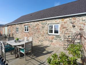 a patio with a table and chairs and a brick building at Tan Twr - Chellow Cottage in Dwyran