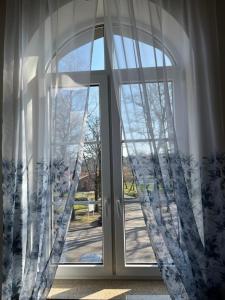 una puerta de cristal abierta con cortinas delante en APARTAMENT SPALSKIE KLIMATY, en Spała