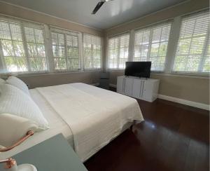 1 dormitorio con 1 cama blanca grande y ventanas en Casa Randa espaciosa y encantadora cerca a canal, en Panamá
