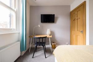 1 dormitorio con escritorio, cama y TV en la pared en Modern 3-bed Duplex Apartment in Fitzrovia near Oxford Street, en Londres