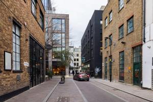 a car is parked on a street between buildings at Spacious & Bright Loft Apartment - Shoreditch in London