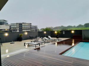 a rooftop patio with a swimming pool and lounge chairs at Mkhonto-PR The Millenial Durban, Umhlanga in Durban