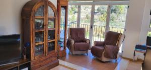 a living room with two chairs and a entertainment center at APARTAMENTO VISTASALRIO ADRIANA,Montanejos in Montanejos