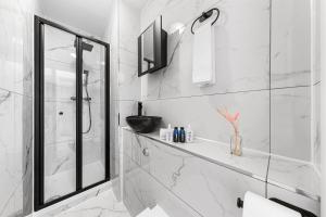 a white bathroom with a shower and a sink at Stylish One Bedroom Flat - Sleeps 4 - Near Primrose Hill, Lord's Cricket Ground, Camden Market - Finchley Road Station - Central London NW3 in London