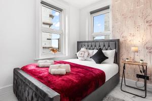 a bedroom with a large bed with a red blanket at Stylish One Bedroom Flat - Sleeps 4 - Near Primrose Hill, Lord's Cricket Ground, Camden Market - Finchley Road Station - Central London NW3 in London