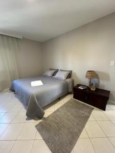 1 dormitorio con 1 cama y 1 mesa con lámpara en Apartamento NOVO no centro/Via Gastronômica en Lages