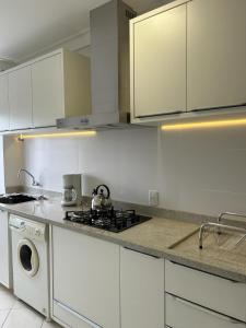 a kitchen with a stove and a washing machine at Apartamento NOVO no centro/Via Gastronômica in Lages