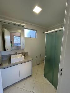 ein Bad mit einem Waschbecken und einer Glasdusche in der Unterkunft Apartamento NOVO no centro/Via Gastronômica in Lages