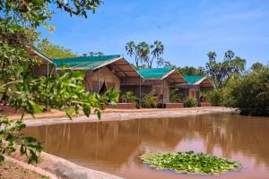 a house with a pond in front of it at BoraBora Wildlife park and Luxury Tented Safari Camp Diani in Diani Beach