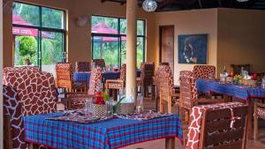 jadalnia ze stołami żyrafowymi i krzesłami w obiekcie BoraBora Wildlife park and Luxury Tented Safari Camp Diani w mieście Diani Beach