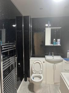 y baño con aseo y lavamanos. en Modern 3 bed house for 8 guest en Nevendon