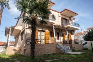 a house with a palm tree in front of it at Βastasio Apartments Pefkochori in Pefkohori