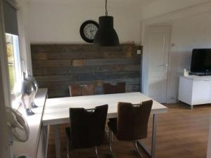Una mesa de comedor con sillas y un reloj en la pared. en Lovely apartment in Julianadorp, en Julianadorp 10 fotos más