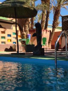 einen Pool mit einem Sonnenschirm, Stühlen und einem Tisch in der Unterkunft Riad Ambelar in Erfoud