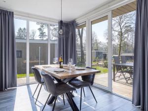 - une salle à manger avec une table, des chaises et des fenêtres dans l'établissement Modern chalet with deck, in a natural area, à Hoenderloo