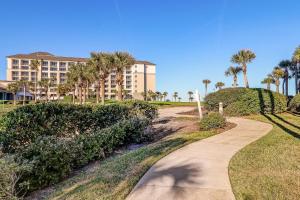 a path in front of a building with palm trees at 58 Ocean Place - Luxury 2BR 2Ba oceanfront condo right next door to the Ritz Carlton in Fernandina Beach