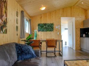 a living room with a couch and a table at Comfortable chalet with combination microwave near the Veluwe in Hoenderloo