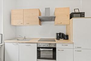 a kitchen with white cabinets and a stove top oven at Dein Zuhause fern von Zuhause in Donawitz