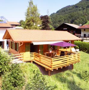 a wooden house with a table and a purple umbrella at Chalet Ramsau in Ramsau