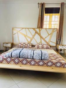 a large bed with a wooden frame in a room at Serenity in style in Kampala