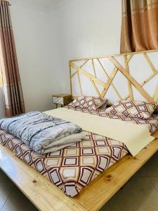 a bed with a wooden frame in a room at Serenity in style in Kampala