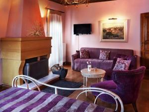 a living room with a purple couch and a fireplace at Lousiou Nymphes escape suites in Dimitsana