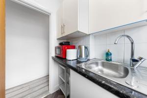 una cucina con lavandino e un apparecchio rosso di Ultra Elegant 2BDR - 10 mins to stadium - Sleeps 5 a Londra