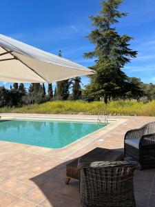 a swimming pool with two chairs and a white umbrella at Casa Galiana. in Argés