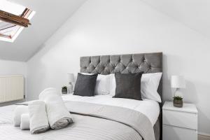 1 dormitorio blanco con 1 cama grande con almohadas blancas en Ultra Elegant 2BDR - 10 mins to stadium - Sleeps 5, en Londres