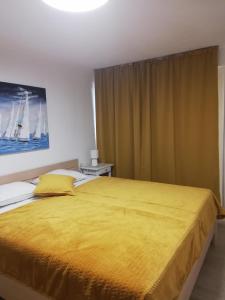 MundanijeにあるApartments Tinjarosaのベッドルーム1室(大型ベッド1台、黄色のベッドカバー付)