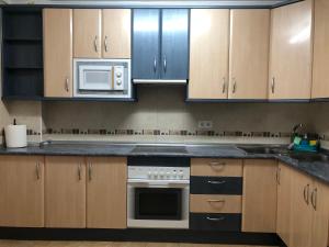 cocina con armarios de madera, fogones y microondas en Apartamento Almanzor II, en Morche 21 fotos más