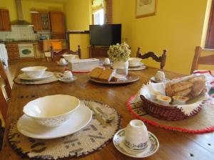 una mesa de madera con platos, tazones y pan. en La Superba Ca' Zeneize, en Foiano della Chiana