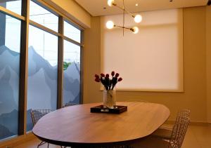 a dining room with a table with flowers in a vase at Roomie Salta by DOT Suites in Salta