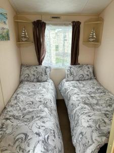 a small room with two beds and a window at 519 Family Caravan at Golden Gate Holiday Centre, Sleeps 6 in Abergele