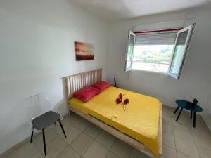 een slaapkamer met een geel bed met rode kussens en een raam bij T2 Climatisé avec Jacuzzi à 5 minutes des plages in Les Trois-Îlets