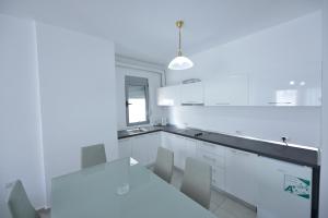 a white kitchen with white cabinets and a table at Aparthotel Miramare in Sarandë