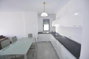 a kitchen with white cabinets and a dining table at Aparthotel Miramare in Sarandë