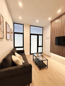 ein Wohnzimmer mit einem schwarzen Sofa und Fenstern in der Unterkunft Estudio a Estrenar a metros de los Jardines del Turia in Valencia