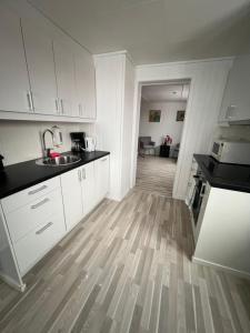 a kitchen with white cabinets and a wooden floor at Live Lofoten Fishermen's Cabins in Stamsund