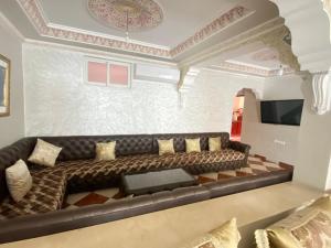 a living room with a leather couch and a tv at Lina confort a tanger in Tangier