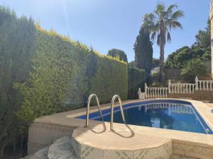 a swimming pool with a chair in front of a yard at Encantadora VILLA con piscina en Playa Flamenca in Alicante