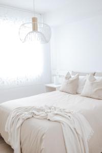 a white bedroom with a white bed and a chandelier at Casa da Sereia in Leiria